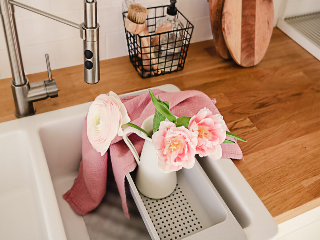 white ceramic sink, faucet, and pink flowers in a vase